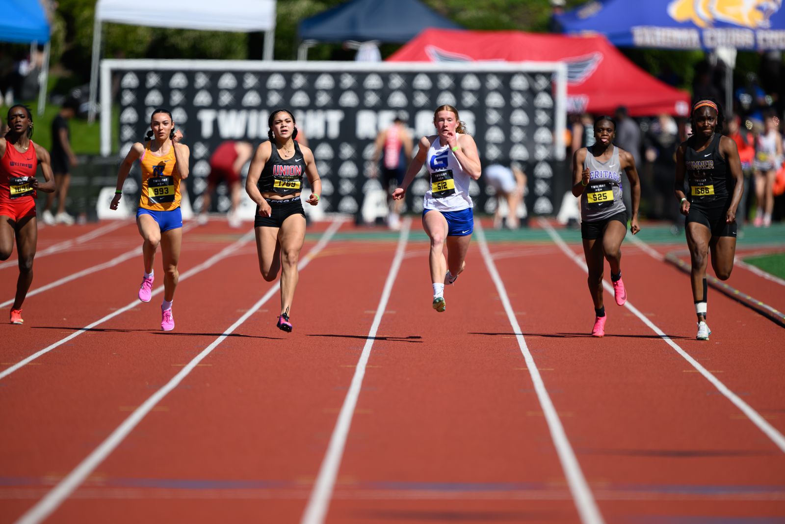 Sprinters in six lanes at the 2026 Twilight Relays finish