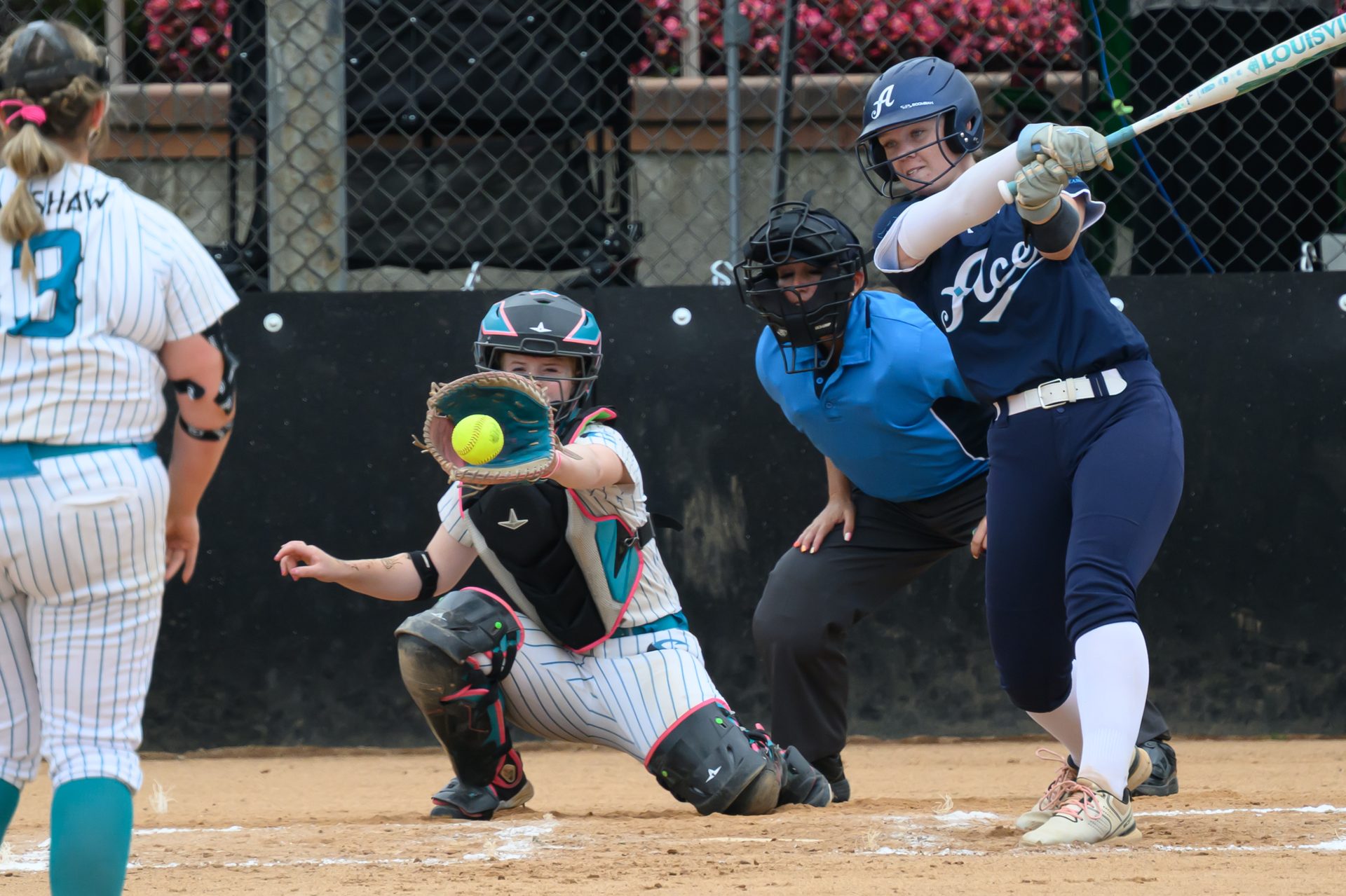 The batter commits to a full swing while the catcher stretches out to snag the pitch in her mitt. 2026 TC World Series Softball, Portland Oregon, 2026.