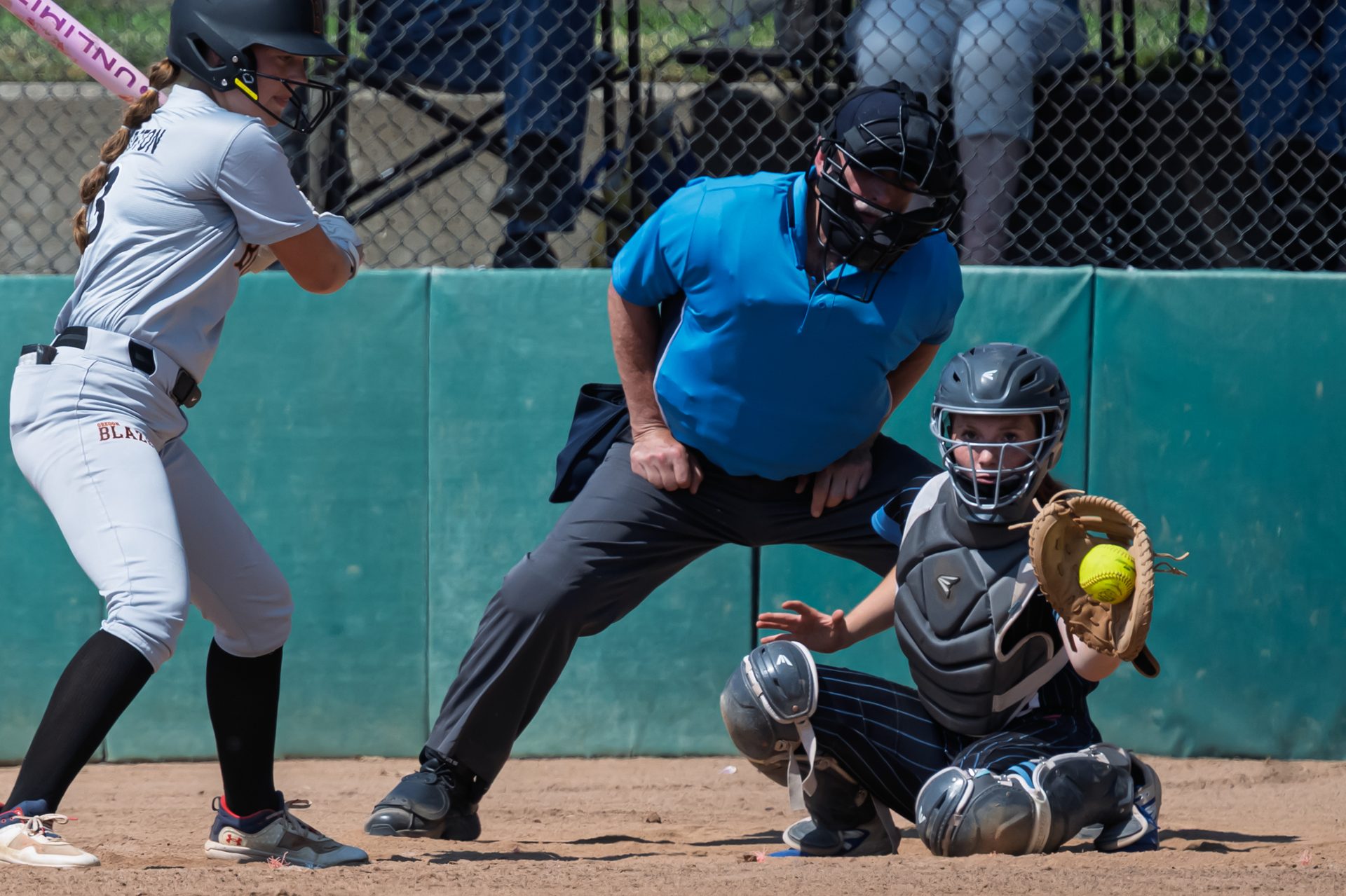 The catcher squares up low behind the plate, glove open, as the ball settles into the pocket right in front of the watching umpire and batter. 2026 TC World Series Softball, Portland Oregon, 2026.