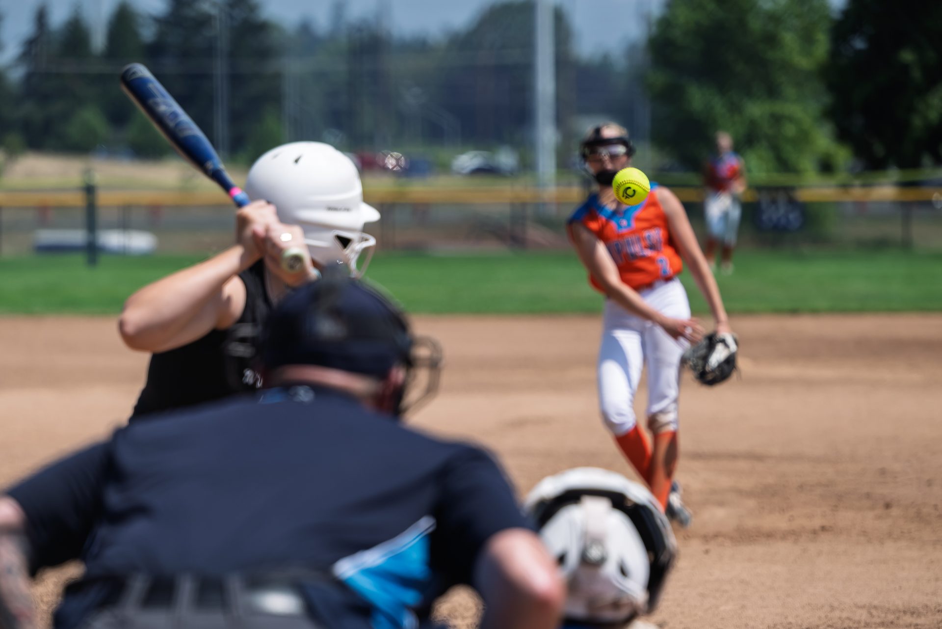 The bright yellow ball hangs in the air just past the plate as the batter watches it close in. 2026 TC World Series Softball, Portland Oregon, 2026.