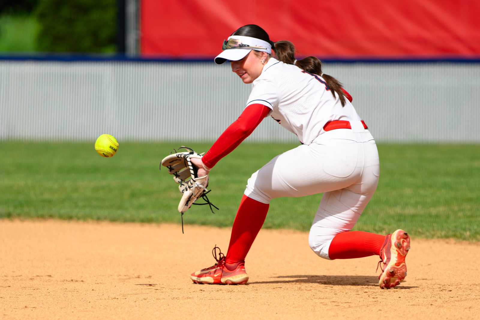 Westview softball infielder drops to one knee to field a low ground ball during a senior night game.