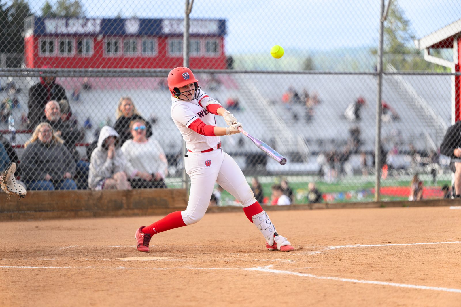 Westview softball batter swings through the pitch and connects with the ball during a senior night game.